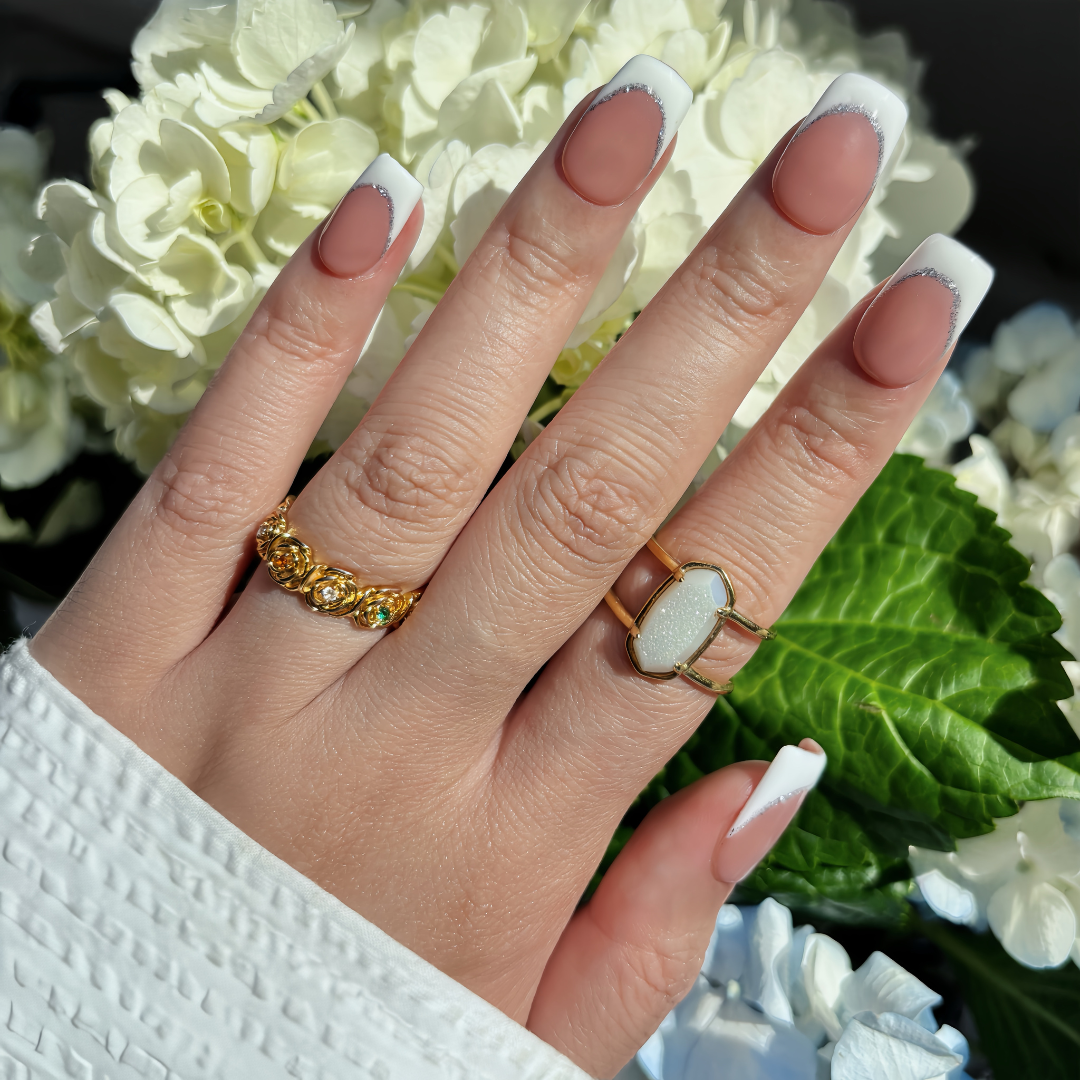 Pinkie Promise Nails Press-Ons Reusable Best Press-on Nails Salon Quality Nails at home Bianca Hand Image Build Your Kit Press-On Nails Bianca Medium Square ,Hand with gold rings and manicured nails in front of white flowers