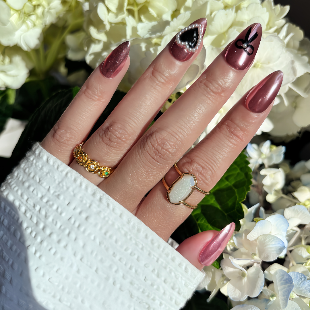 Pinkie Promise Nails Press-Ons Reusable Best Press-on Nails Salon Quality Nails at home Amina Medium Almond Hand Image Build Your Kit Press-On Nails, Hand with maroon nail polish and gold rings against a floral background
